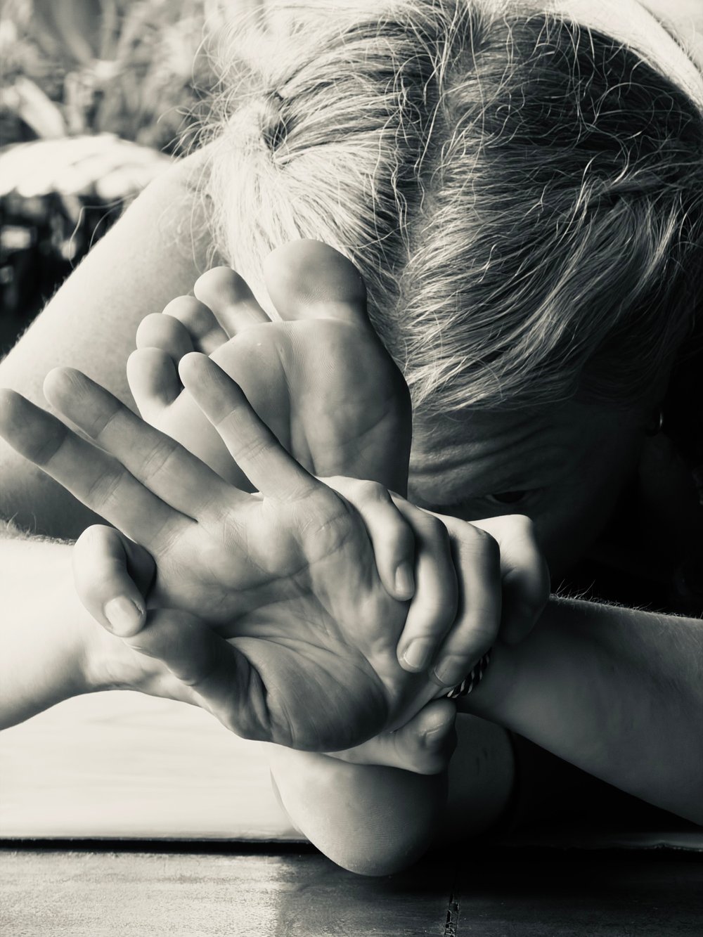 Close, intimate detail of hands and feet in a seated yoga pose